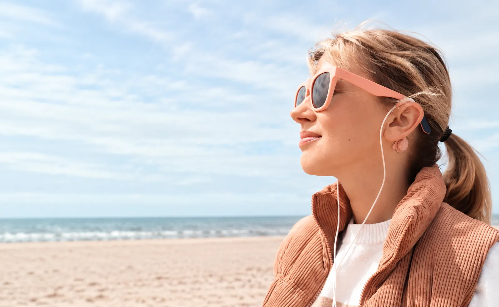 A woman relaxing on the beach wearing the Roga device
